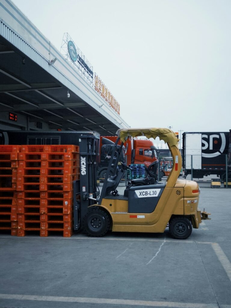 Forklift ve yanında istiflenmiş turuncu plastik paletler